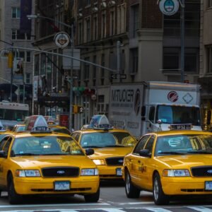 yellow taxi cab on road near white concrete building during daytime